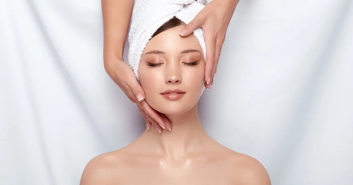 Woman receiving a relaxing facial treatment in Evans, GA, with a towel wrapped around her hair.